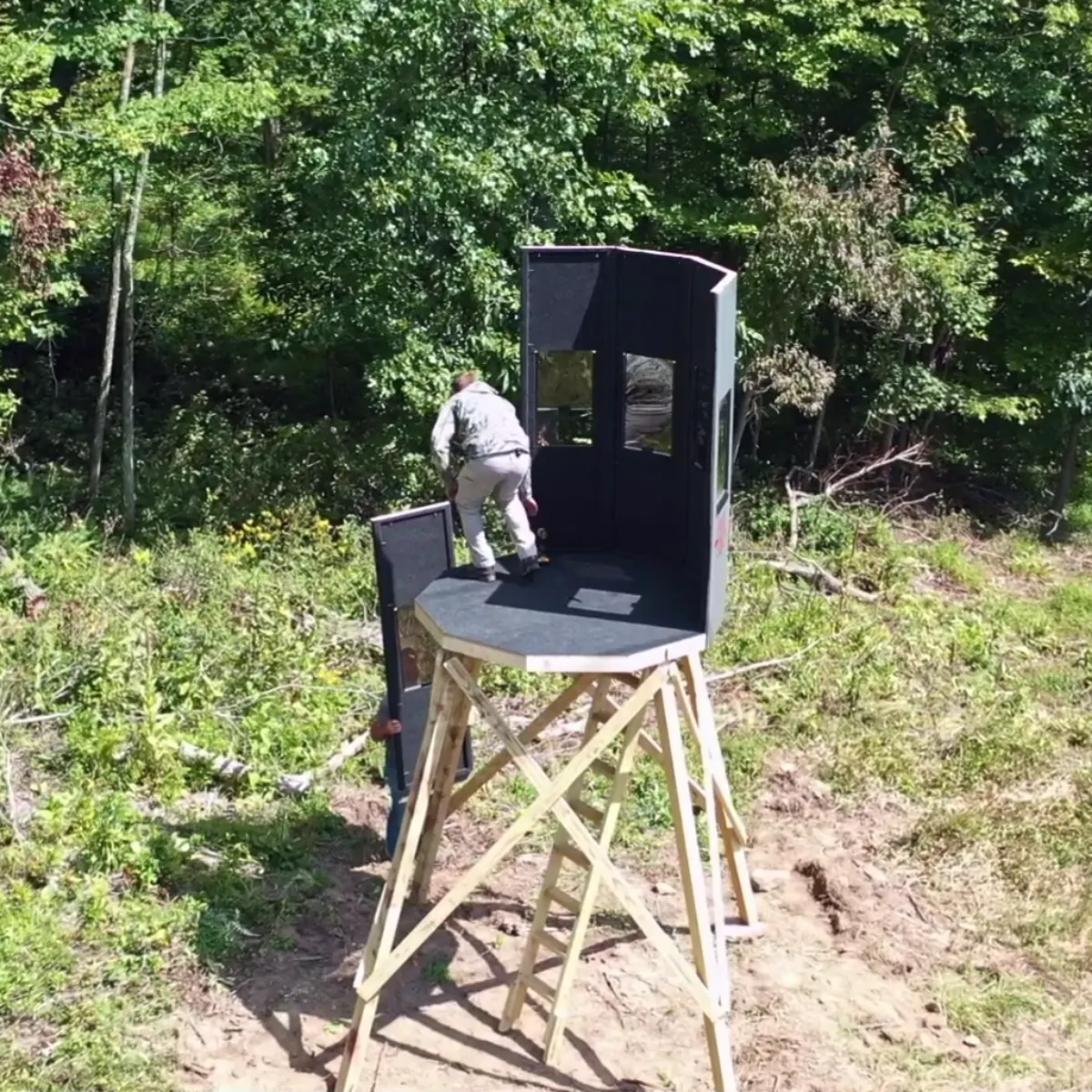 A blind standing on a wooden tower, panels assembled, door open.