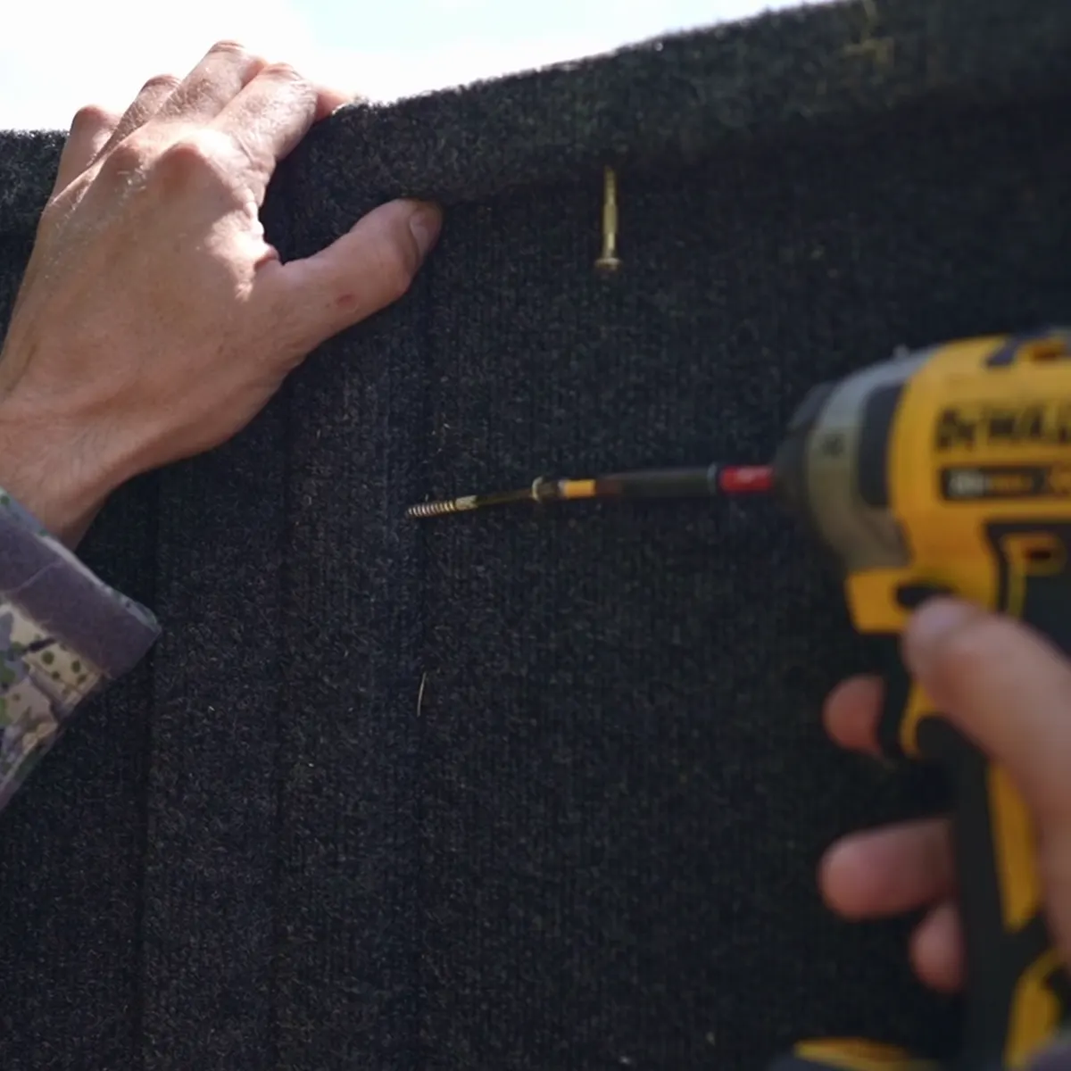 Driving a pre-started screw through a carpeted wall panel.