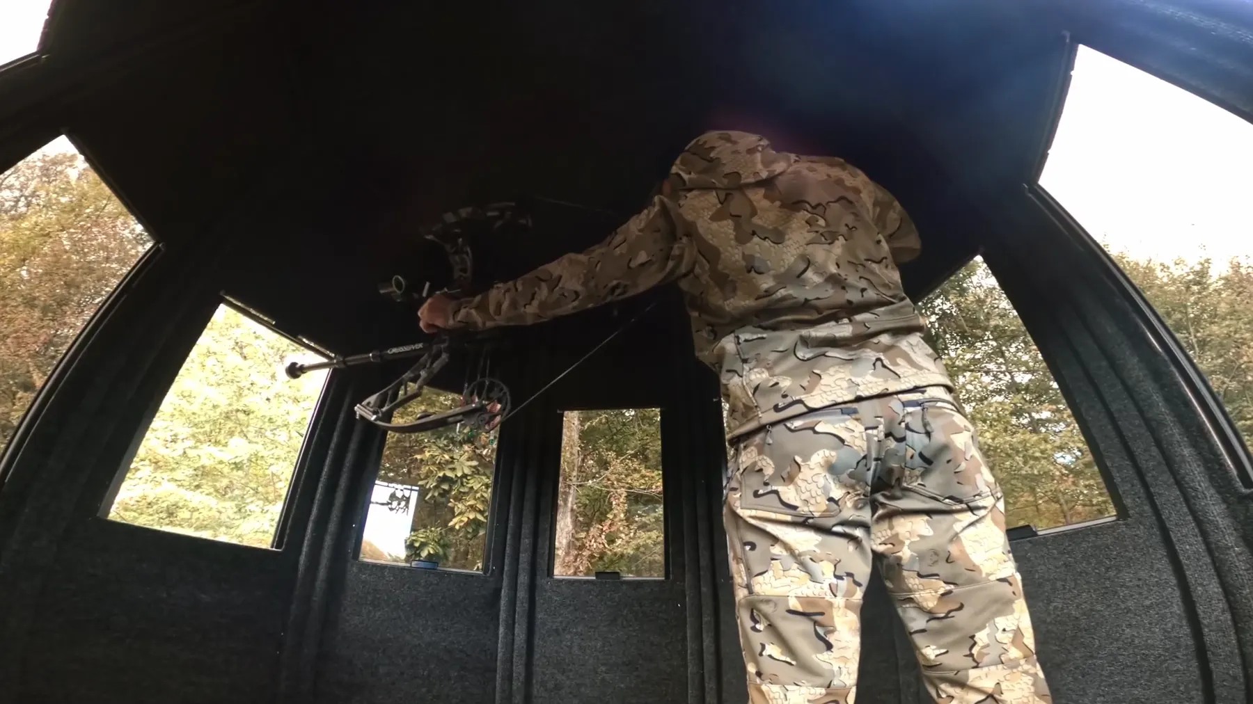 A hunter at full draw, standing, inside a NXTGen blind.