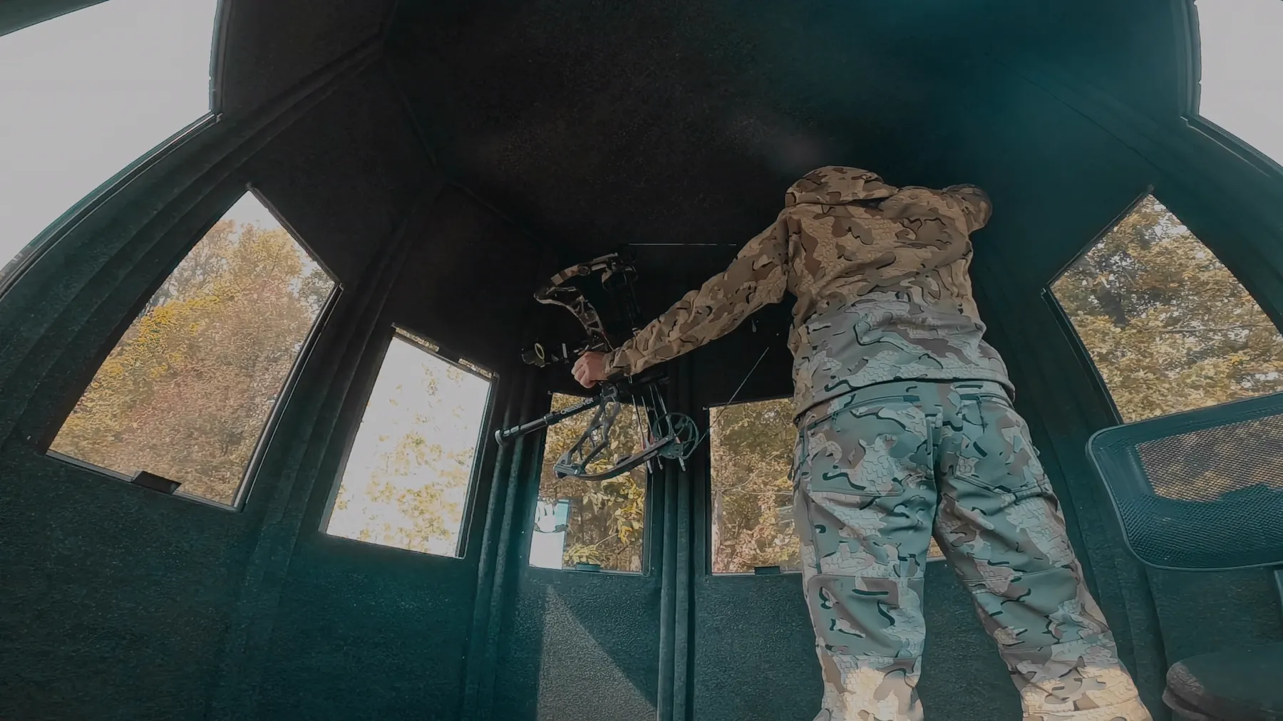 A hunter at full draw inside a NXTGen blind with room above their head.